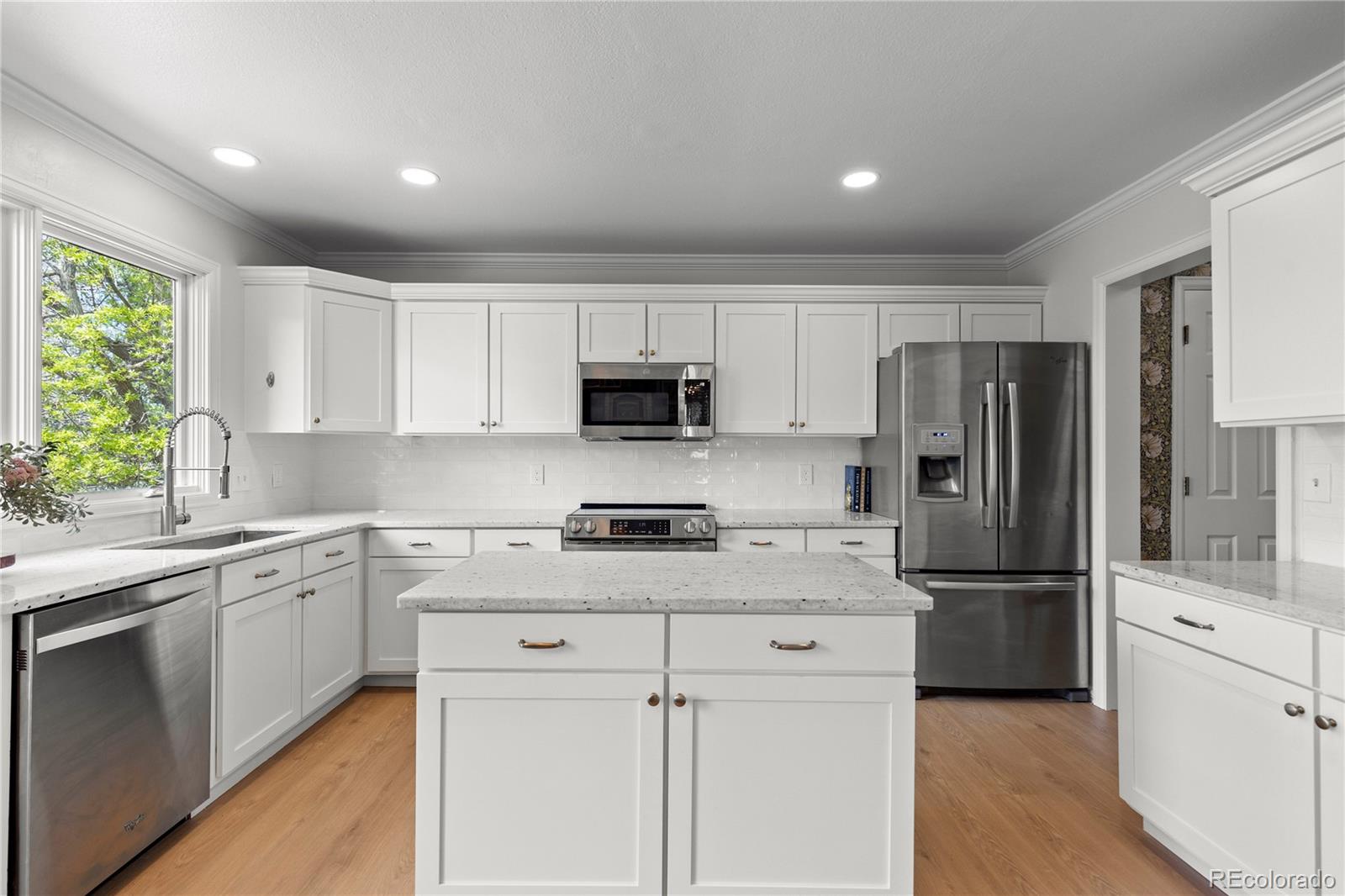 9362 Cornell Circle Highlands Ranch, CO 80130 - Photo 12 of 44 a kitchen with white cabinets and stainless steel appliances
