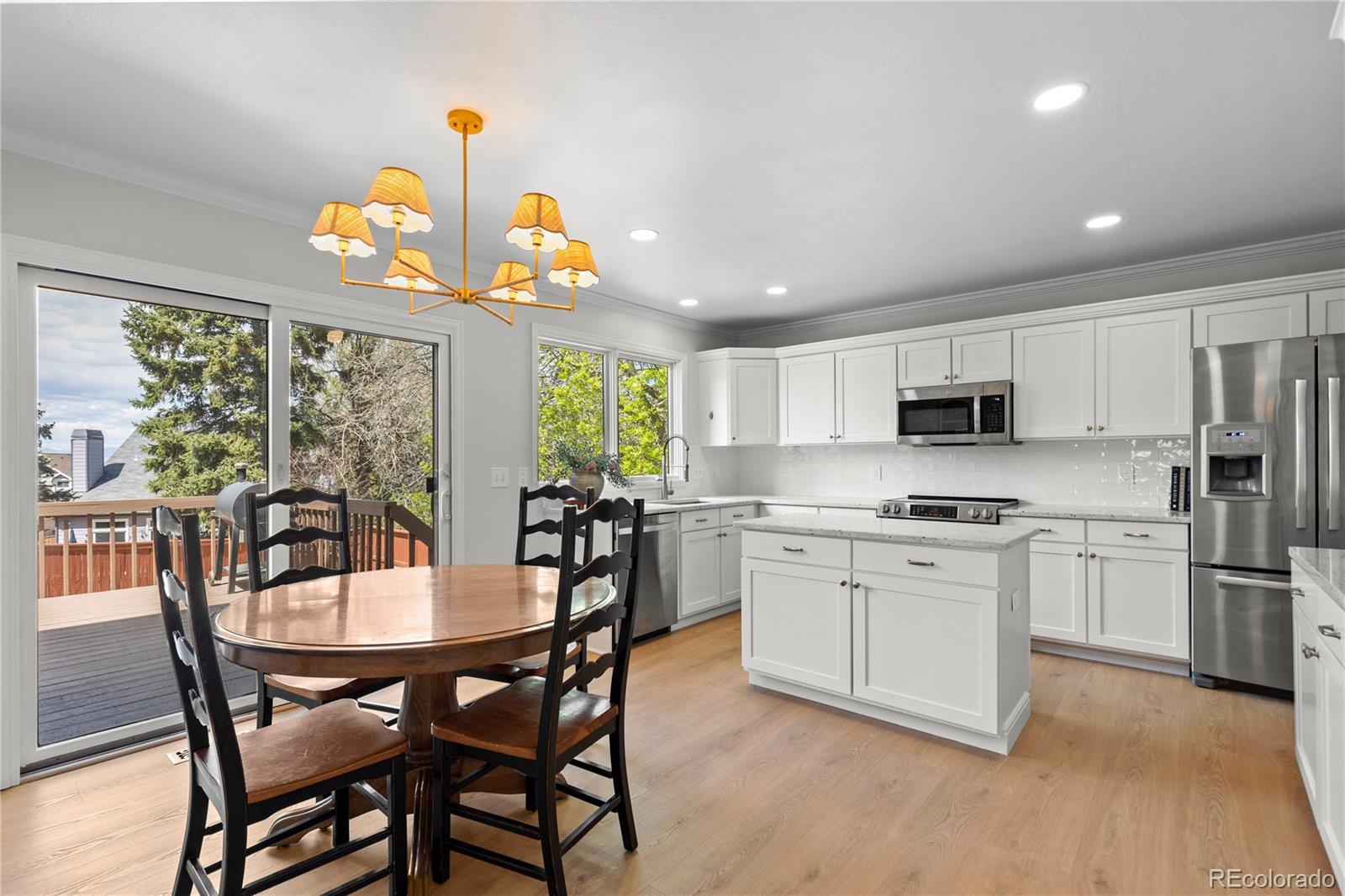 9362 Cornell Circle Highlands Ranch, CO 80130 - Photo 17 of 44 a kitchen with stainless steel appliances granite countertop a dining table chairs stove refrigerator and microwave
