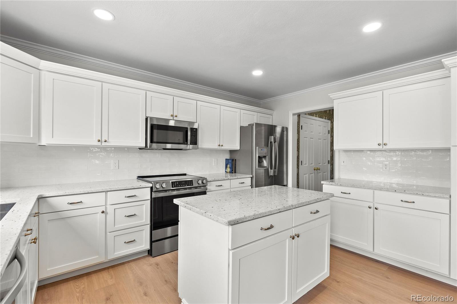 9362 Cornell Circle Highlands Ranch, CO 80130 - Photo 10 of 44 a kitchen with white cabinets and stainless steel appliances