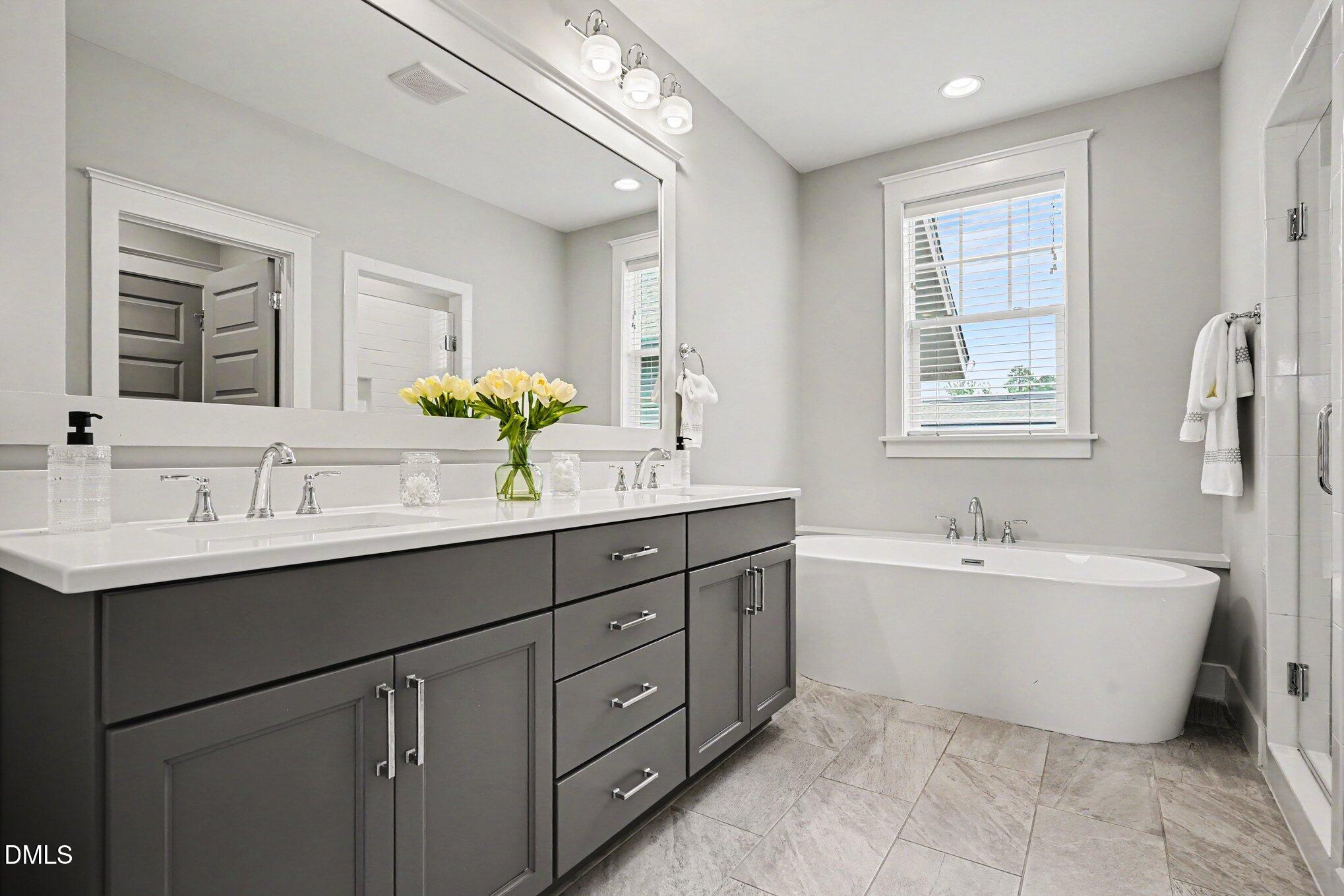 824 Watercolor Way Durham, NC 27713 - Photo 15 of 28 a bathroom with a double vanity sink bathtub large mirror and window