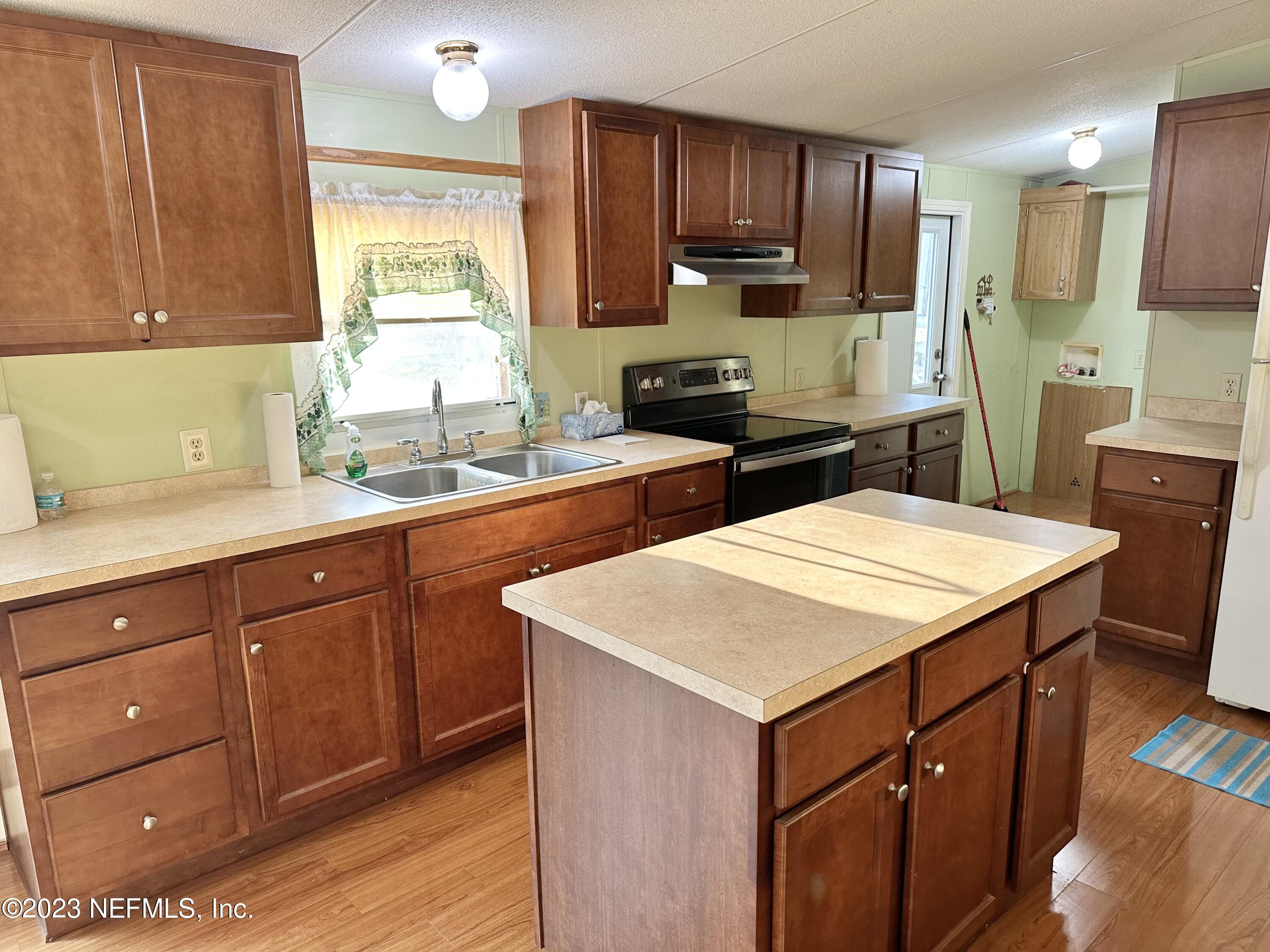 15644 Sears Road Jacksonville, FL 32218 - Photo 14 of 24 a kitchen with a sink a stove cabinets and wooden floor