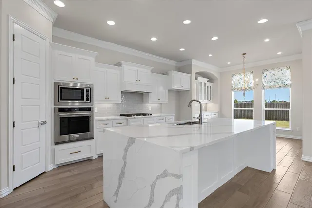 a kitchen with kitchen island a white counter top space stainless steel appliances and cabinets