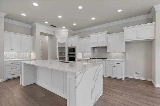 a large white kitchen with kitchen island a sink a stove a refrigerator and white cabinets