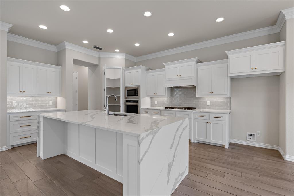 5682 Blackstone Drive Wichita Falls, TX 76310 - Photo 14 of 31 a large white kitchen with kitchen island a sink a stove a refrigerator and white cabinets
