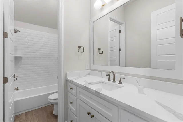 a bathroom with a granite countertop sink a toilet and shower