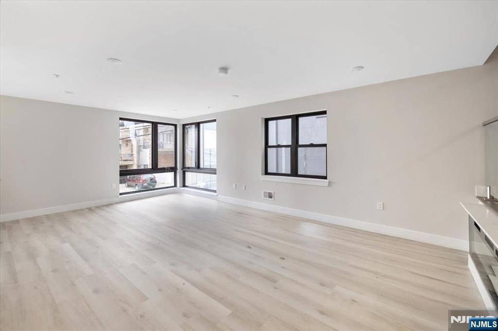 526 64th Street, Unit 3 West New York, NJ 07093 - Photo 3 of 19 a view of an empty room with wooden floor and a window