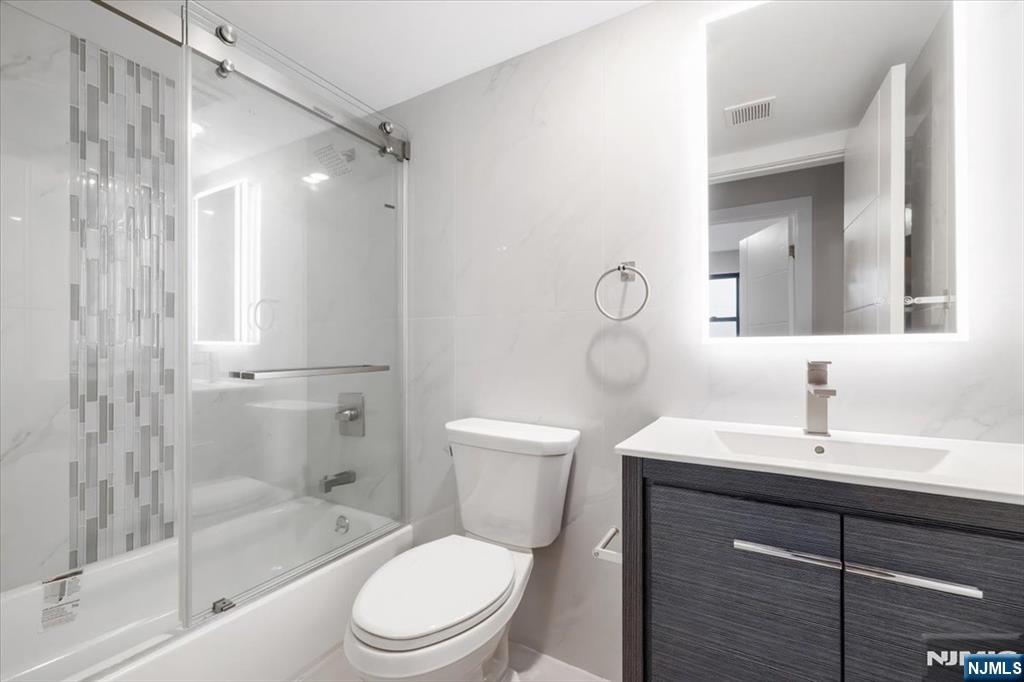 526 64th Street, Unit 3 West New York, NJ 07093 - Photo 7 of 19 a bathroom with a toilet a sink a mirror a bathtub and vanity