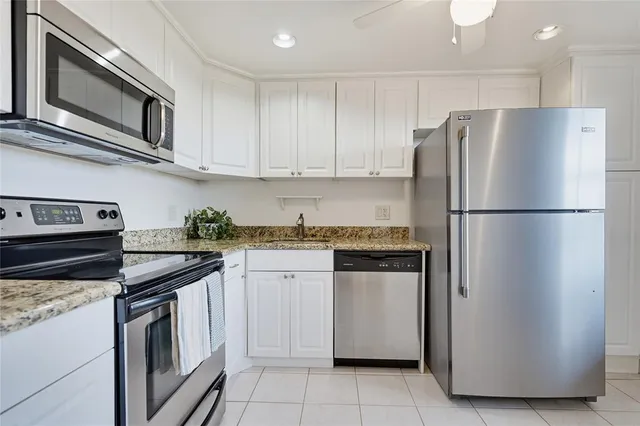 a kitchen with stainless steel appliances granite countertop white cabinets a refrigerator and a stove top oven