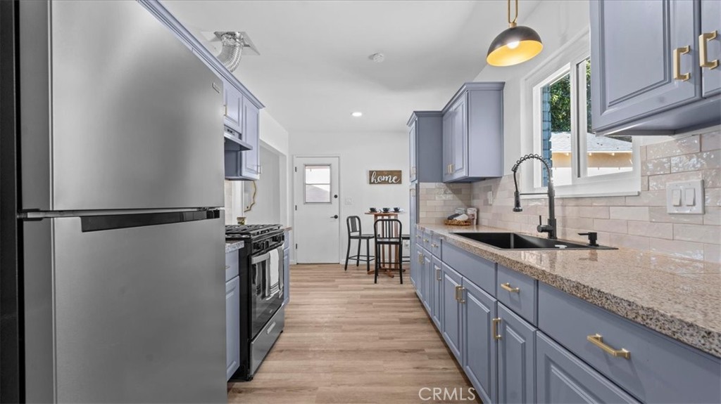 132 South Acacia Avenue Rialto, CA 92376 - Photo 9 of 23 a kitchen with stainless steel appliances granite countertop a sink and a refrigerator