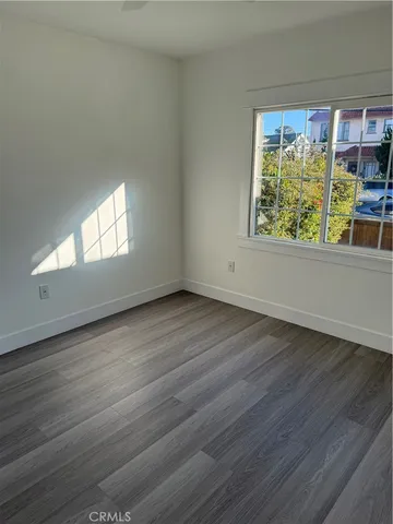 a view of a hallway with wooden floor and a bathroom
