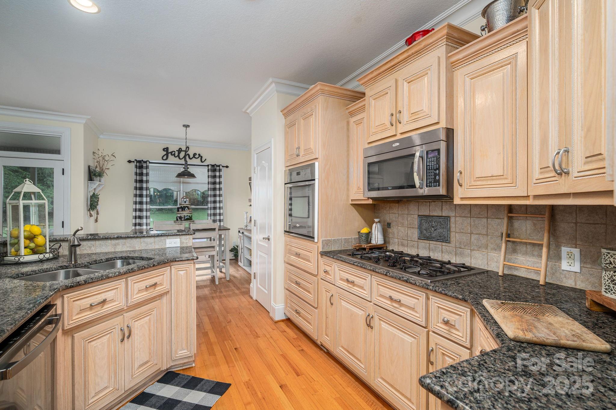 543 Roy Eaker Road Cherryville, NC 28021 - Photo 16 of 43 a kitchen with stainless steel appliances granite countertop a stove top oven a sink dishwasher and cabinets with wooden floor
