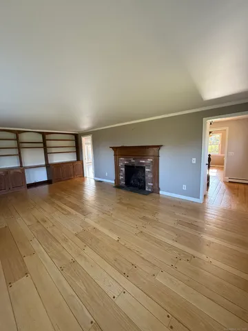 a view of empty room with a fireplace and wooden floor