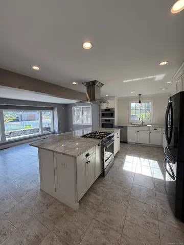 a large kitchen with stainless steel appliances granite countertop a large counter top and a stove top oven