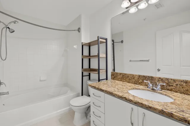 a bathroom with a granite countertop sink a toilet and shower