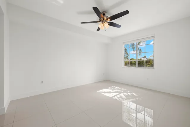an empty room with windows and fan
