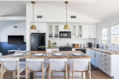 a kitchen with stainless steel appliances kitchen island granite countertop a sink a stove a table and chairs