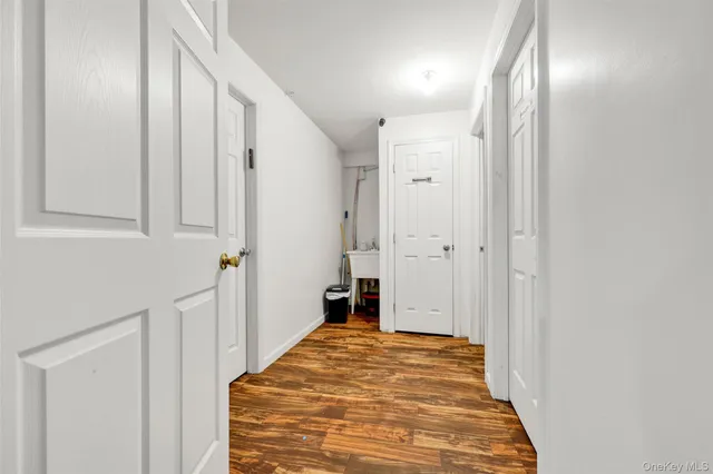 a view of a hallway with wooden floor and a bathroom