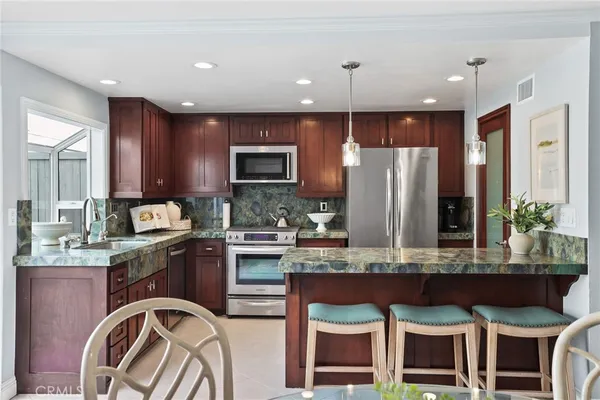 a kitchen with stainless steel appliances granite countertop a stove top oven a sink and a refrigerator