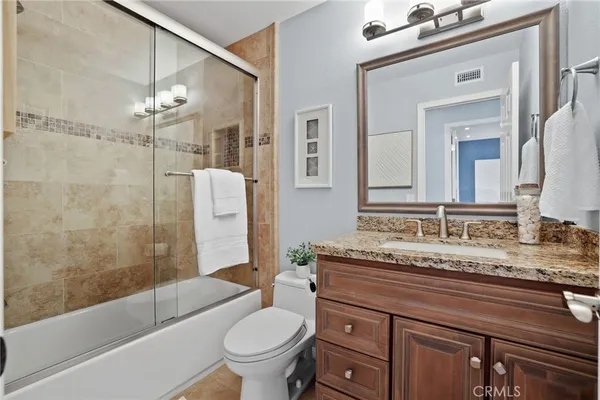 a bathroom with a granite countertop sink toilet mirror and shower