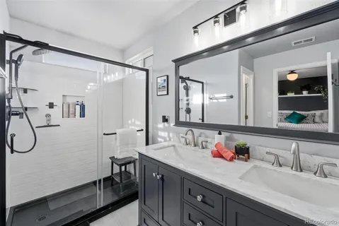 a bathroom with a granite countertop sink a mirror a vanity and shower