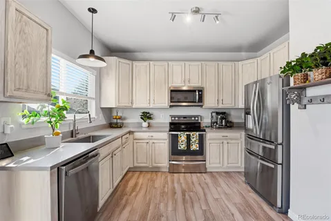 a kitchen with granite countertop a refrigerator a sink dishwasher a stove top oven a refrigerator with wooden floor