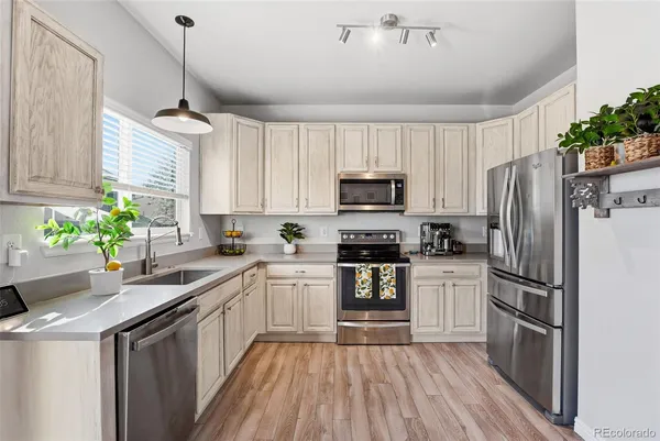 a kitchen with granite countertop a refrigerator a sink dishwasher a stove top oven a refrigerator with wooden floor