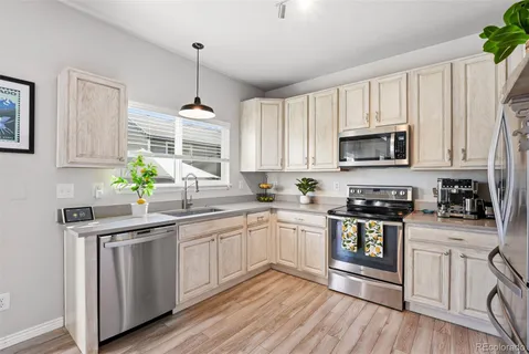 a kitchen with stainless steel appliances granite countertop white cabinets a sink a stove a microwave and wooden floors
