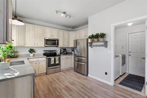 a kitchen with a refrigerator a microwave oven a sink dishwasher and wooden cabinets