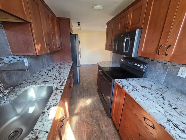 a kitchen with granite countertop a sink stove and cabinets