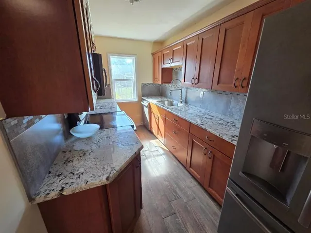 a kitchen with stainless steel appliances granite countertop a sink a stove and a wooden cabinets