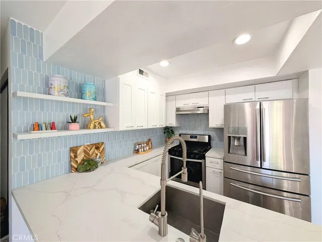 a kitchen with stainless steel appliances granite countertop a refrigerator and a sink