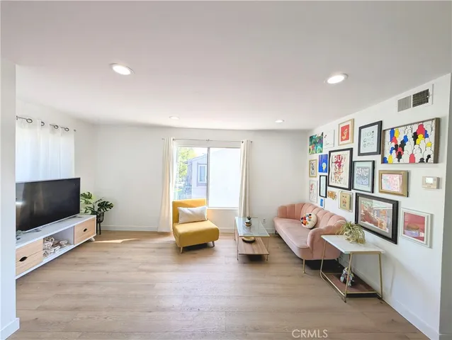a living room with stainless steel appliances kitchen island furniture and wooden floor