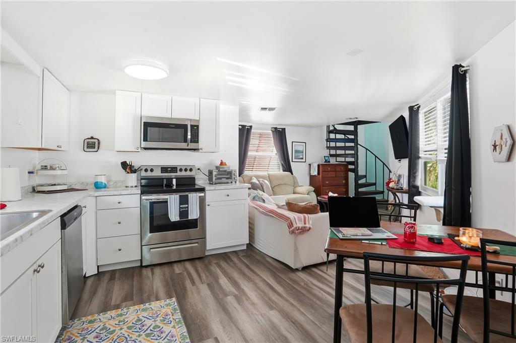 5431 Oak Ridge Avenue Fort Myers Beach, FL 33931 - Photo 18 of 33 a kitchen with stainless steel appliances kitchen island granite countertop a stove top oven a sink dishwasher and white cabinets with wooden floor
