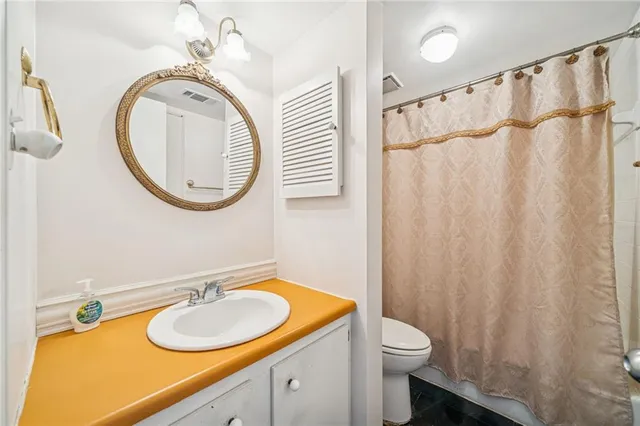 a bathroom with a granite countertop sink toilet and a mirror