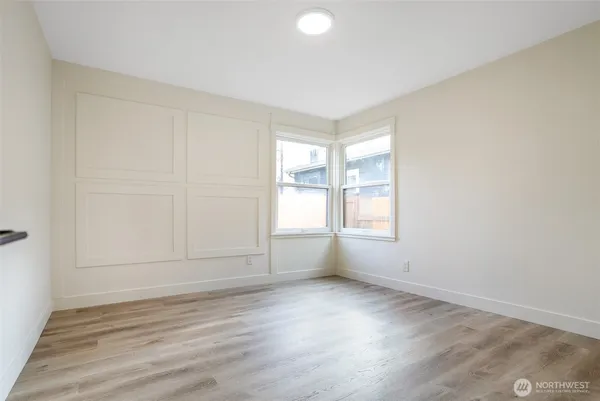 an empty room with wooden floor and windows with curtains