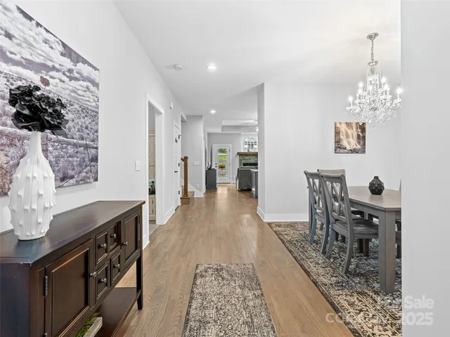 a kitchen with stainless steel appliances granite countertop a stove top oven a sink a dining table and chairs with wooden floor