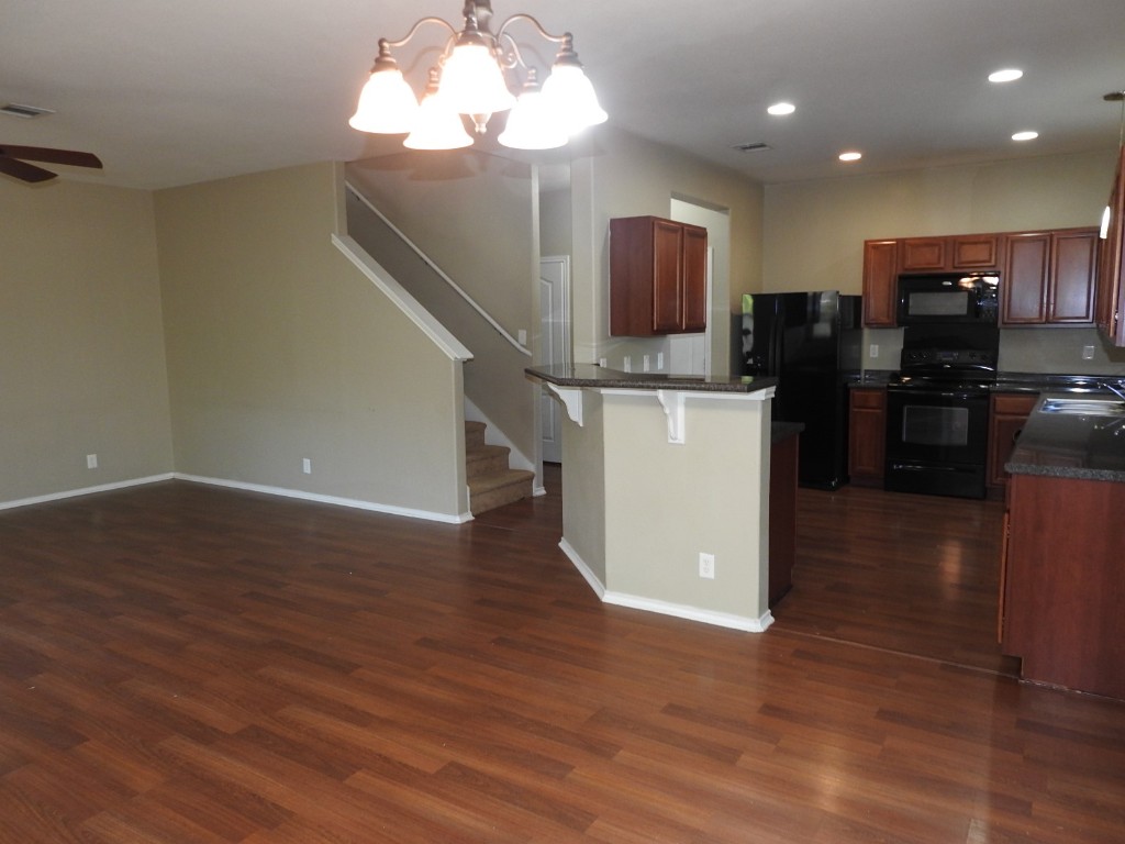 571 New Country Road Kyle, TX 78640 - Photo 9 of 21 a kitchen with stainless steel appliances granite countertop a refrigerator a stove top oven a sink and dishwasher with wooden floor