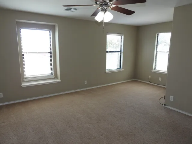 an empty room with a window and a fan