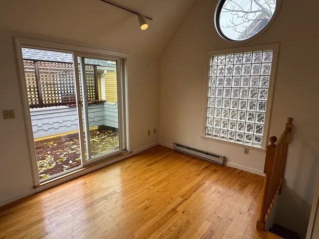 an empty room with wooden floor and windows