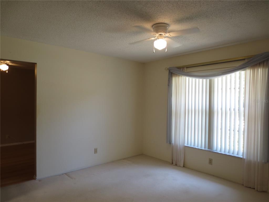 3235 East Dorchester Drive Palm Harbor, FL 34684 - Photo 18 of 47 an empty room with chandelier fan and windows