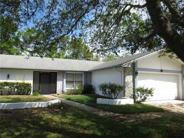 a view of a house with a yard and a large tree