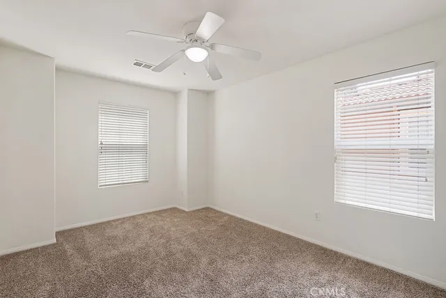 an empty room with windows and ceiling fan