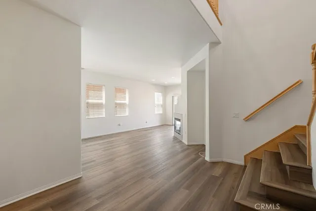 a view of an empty room with wooden floor and stairs