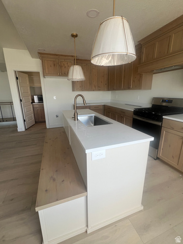 4740 West 25 North West Point, UT 84015 - Photo 5 of 15 Kitchen featuring a central island with a built-in wood-finish bench, an undermount stainless steel sink, and quartz countertops