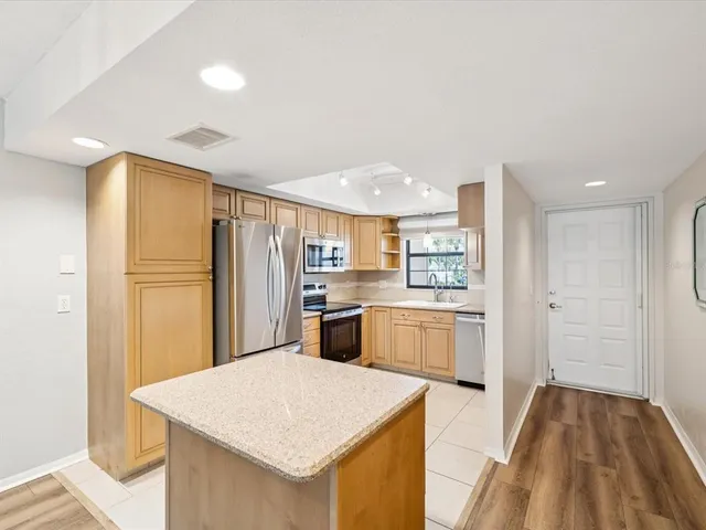 a kitchen with a refrigerator a sink and dishwasher with wooden floor