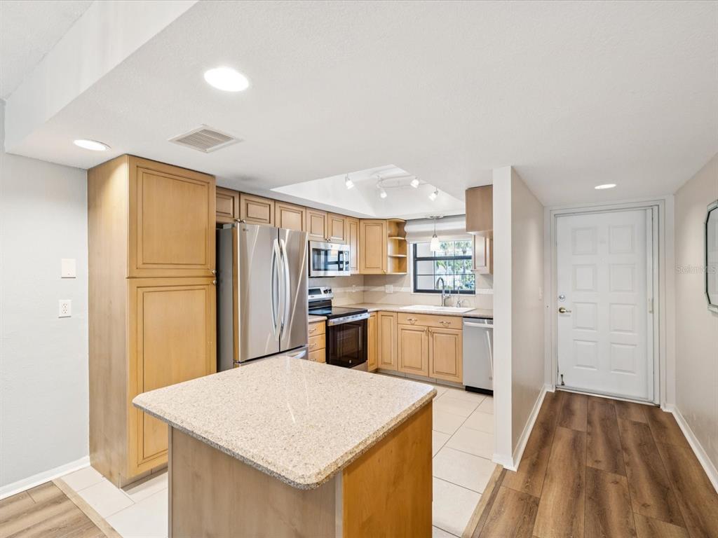 12900 Vonn Road, Unit E203 Largo, FL 33774 - Photo 2 of 26 a kitchen with a refrigerator a sink and dishwasher with wooden floor