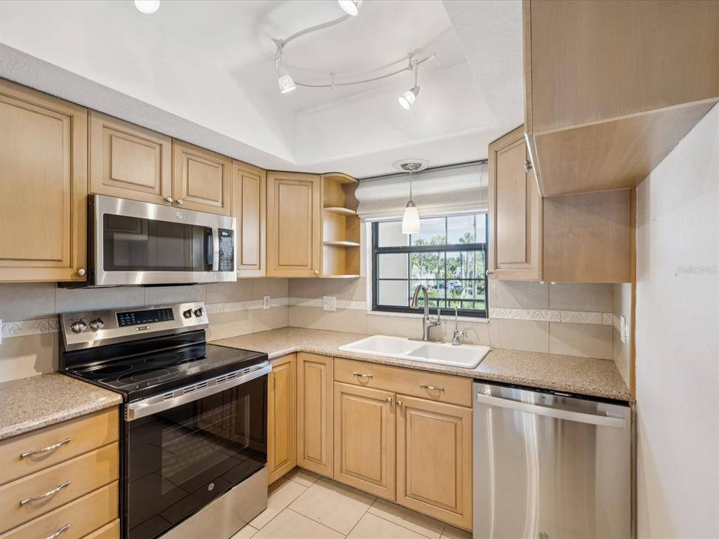12900 Vonn Road, Unit E203 Largo, FL 33774 - Photo 6 of 26 a kitchen with stainless steel appliances granite countertop a sink stove and microwave