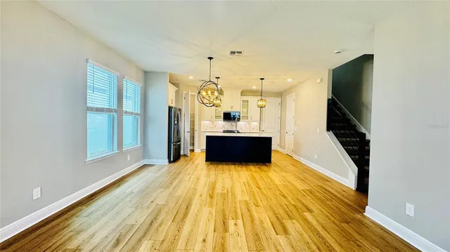 a living room with stainless steel appliances kitchen island granite countertop furniture and a wooden floor