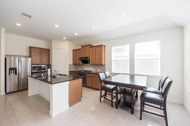 a kitchen with stainless steel appliances a table and chairs in it
