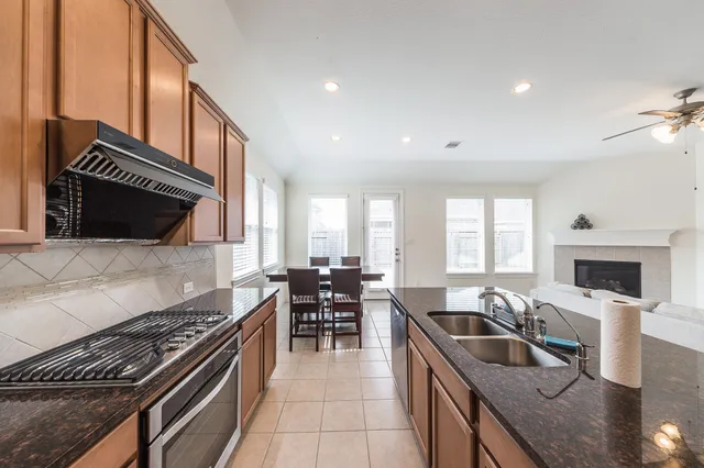 a kitchen with granite countertop a stove top oven a sink a dining table and chairs